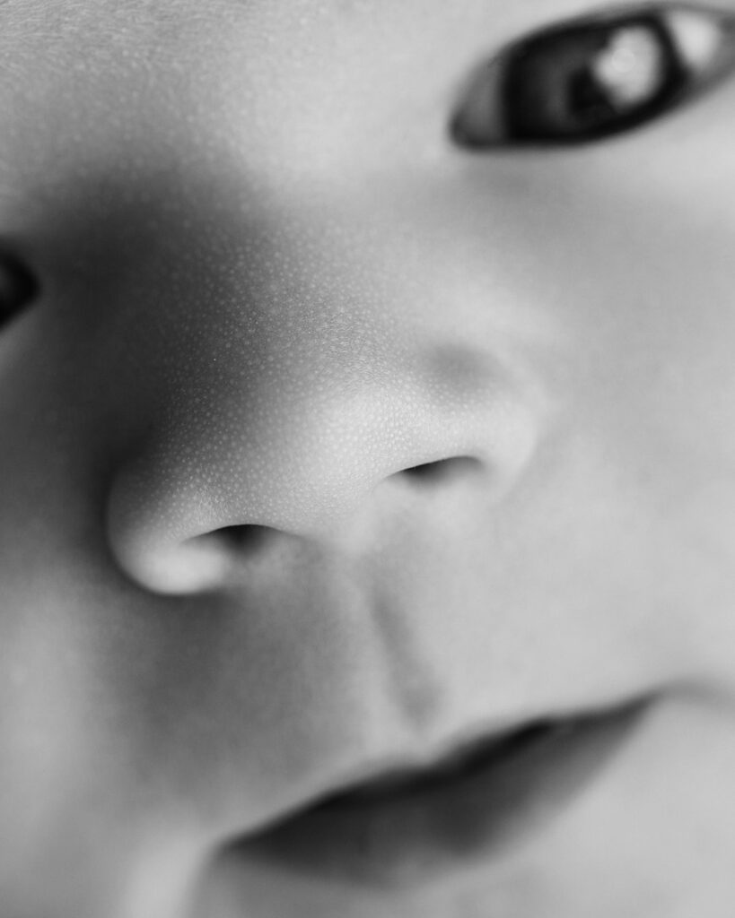 Black-and-white close-up portrait of a newborn baby’s tiny nose and lips, highlighting delicate newborn details.