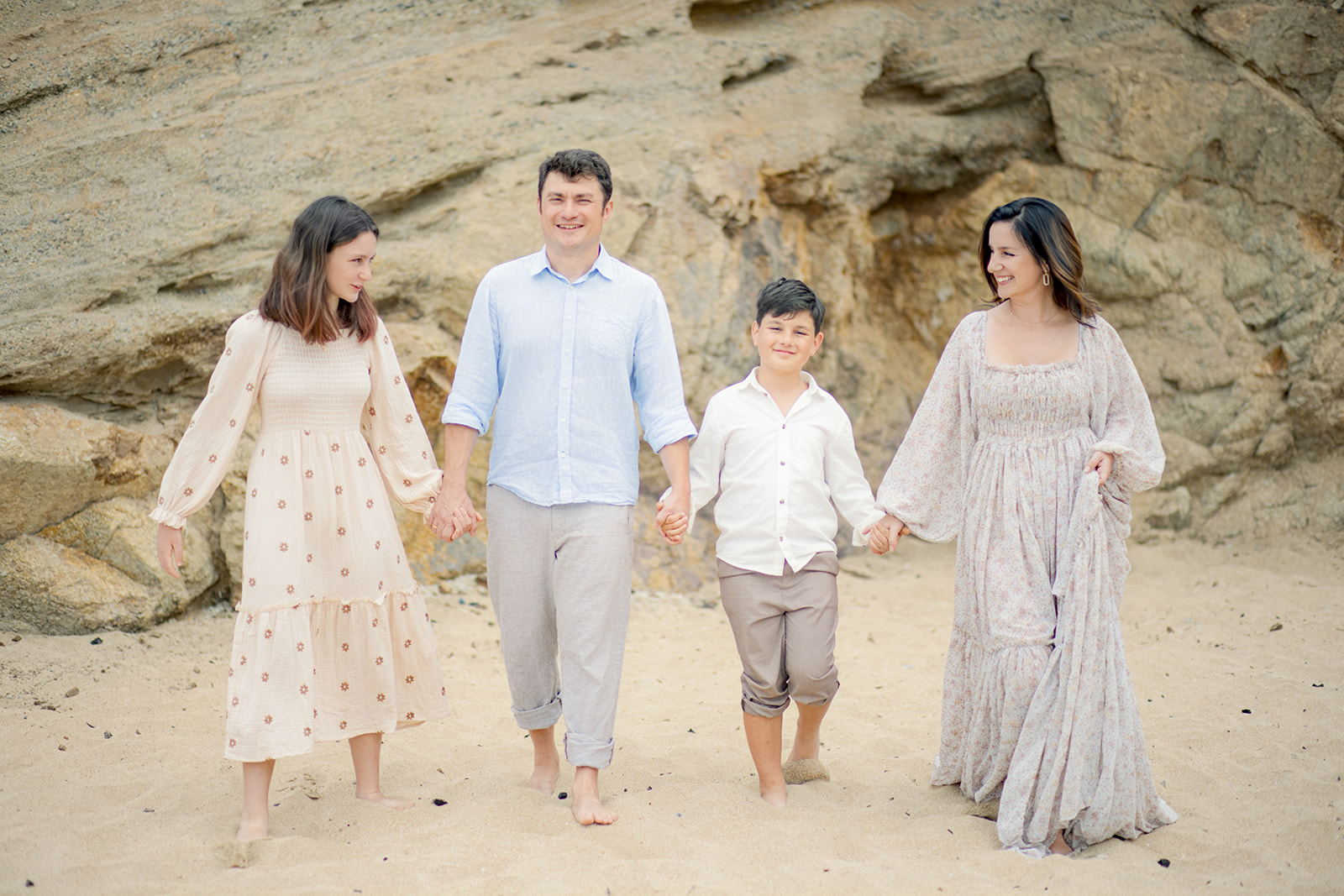 Parents and children walking together along the beach surrounded by coastal cliffs