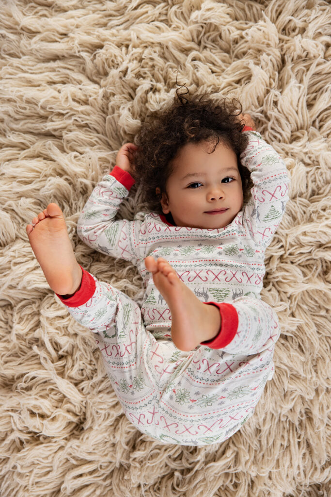 Smiling baby lying on a cozy blanket in a festive Christmas setting