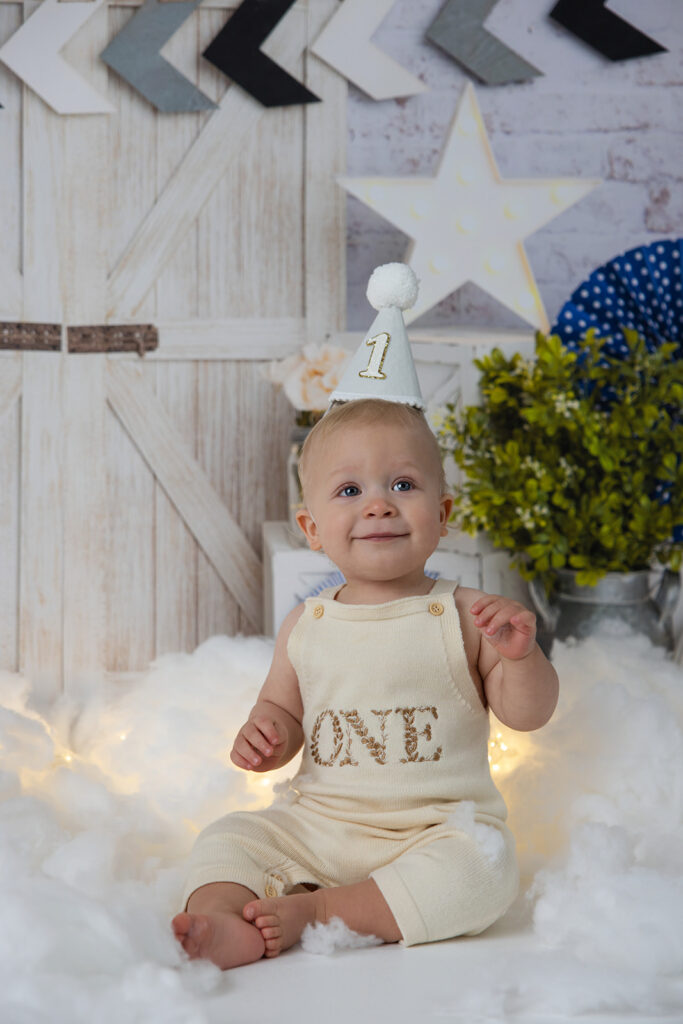 Baby wearing a birthday hat in a rustic bathtub setup during a milestone photography session by FrameIt Bay Area.