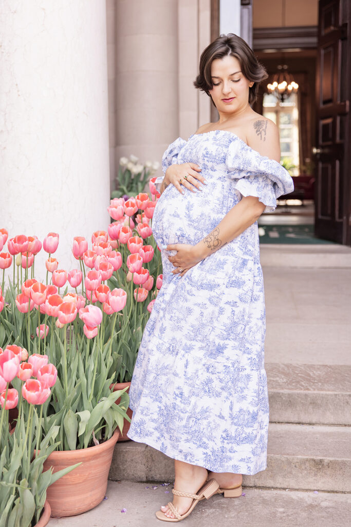 Pregnant woman in blue floral maternity dress posing among flowers at Filoli Garden