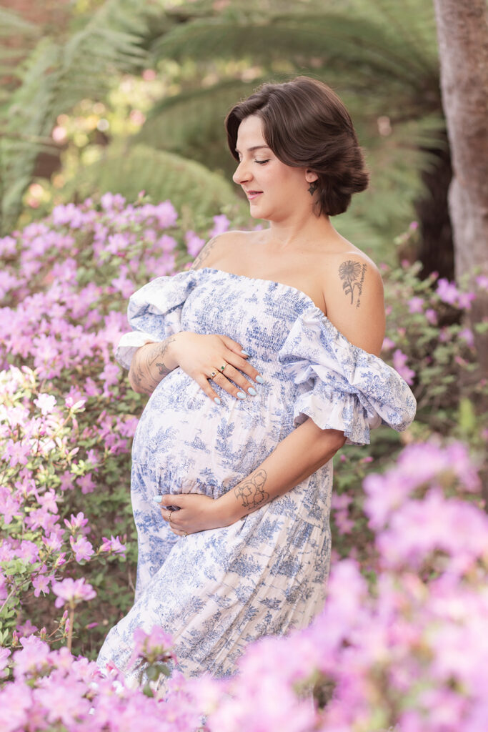 Expectant mother in blue floral maternity dress walking through Filoli Garden during a maternity photoshoot