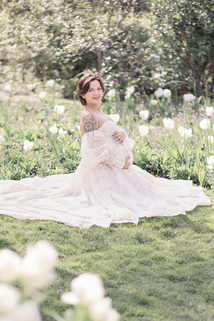 Expectant mother in white maternity dress posing outdoors at Filoli Garden during a maternity photoshoot