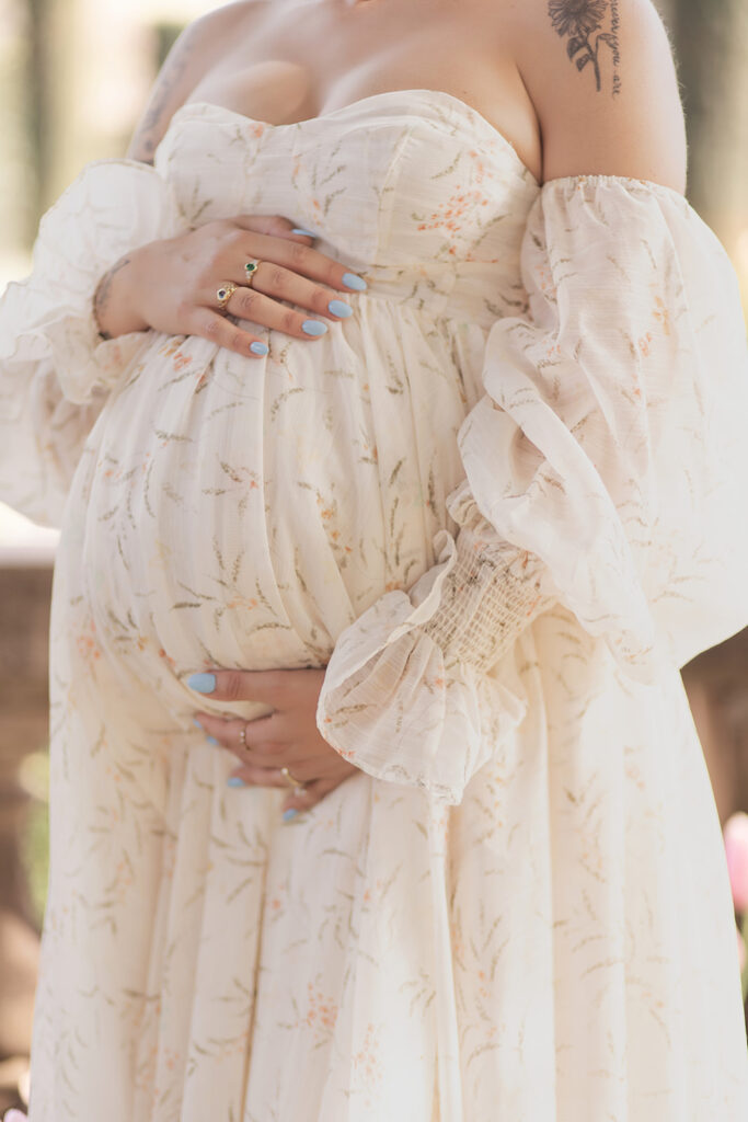 Close-up of expectant mother’s belly and flowing white maternity dress at Filoli Garden