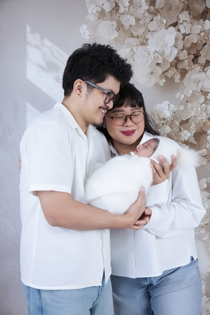 Mother and father lovingly holding their newborn baby together, celebrating family connection and the transition into parenthood.