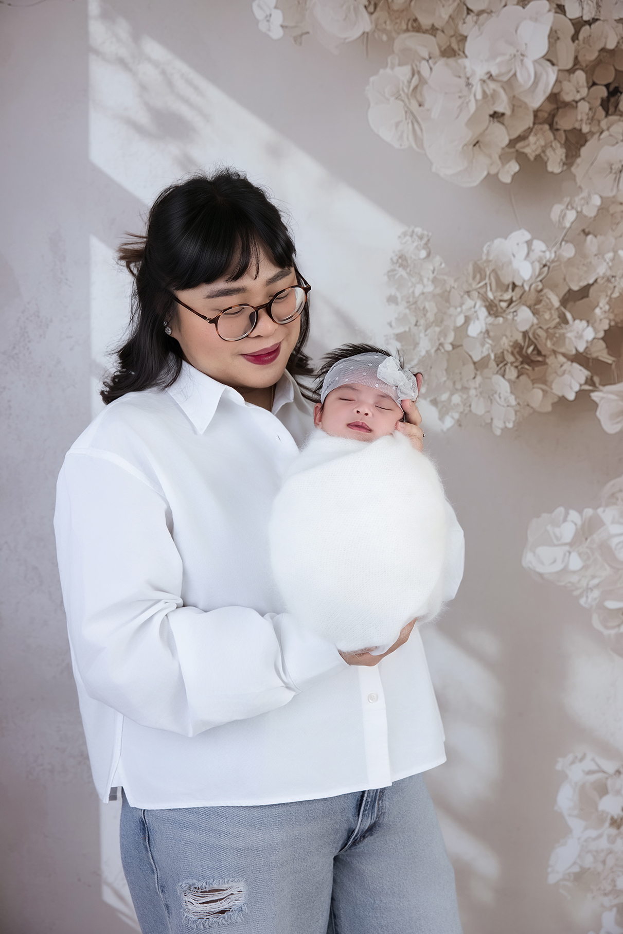 Mother holding her newborn baby wrapped in a white blanket, capturing the tender connection and changing identity of motherhood.
