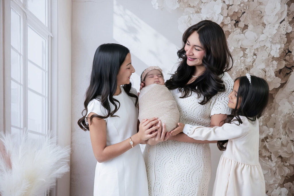 Mother and daughters gathered around their newborn baby for a beautiful family portrait at FrameIt Bay Area studio in San Ramon.