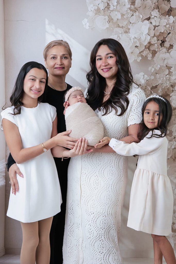 Three generations of women holding and celebrating a newborn baby girl during a San Ramon studio newborn photography session.
