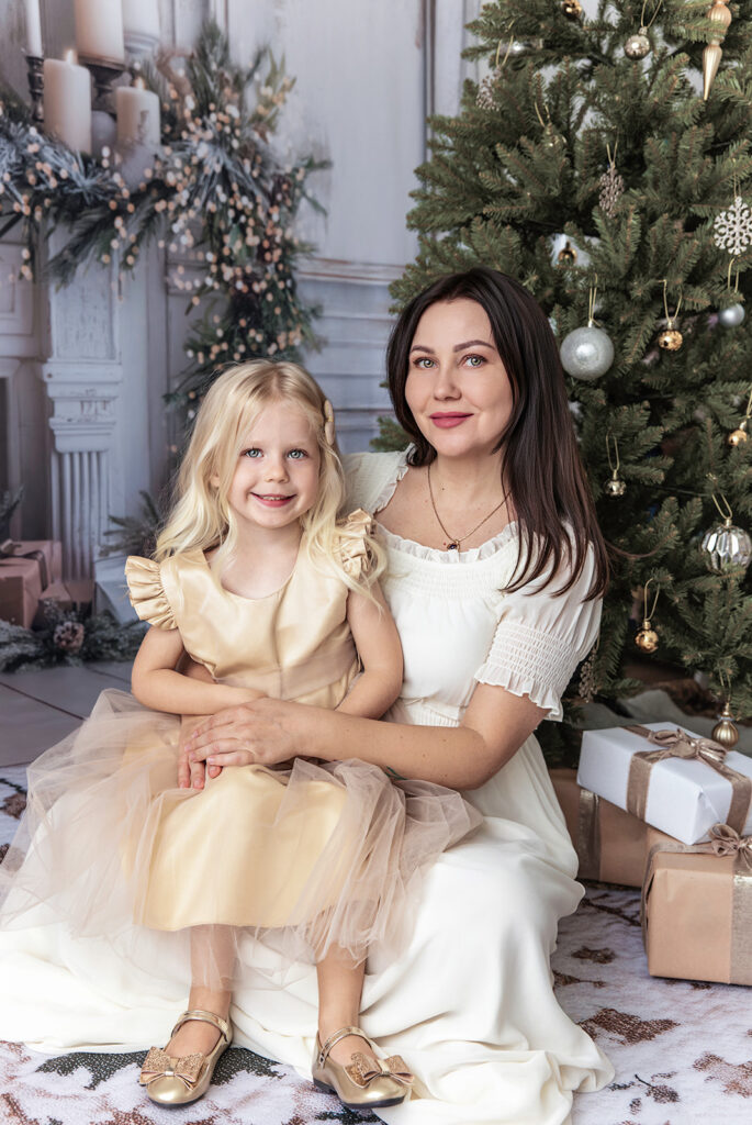 Christmas family photography featuring a mother and daughter beside a decorated Christmas tree