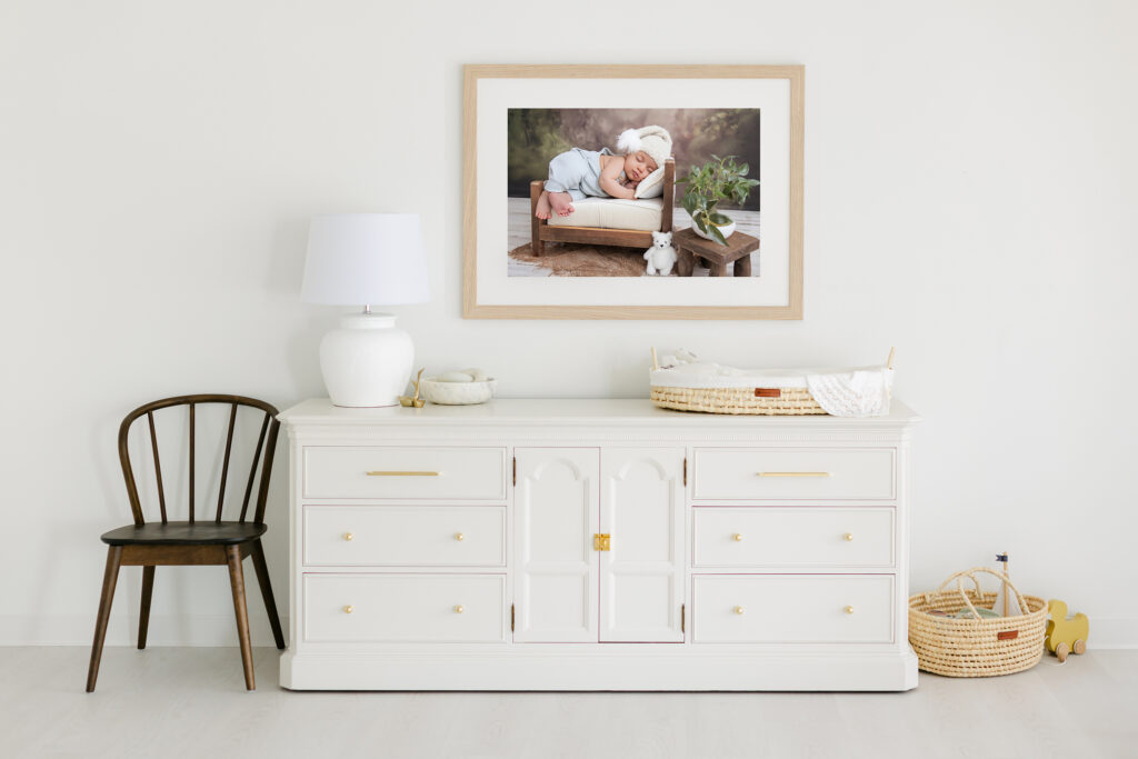 Newborn portrait wall art displayed above a nursery dresser