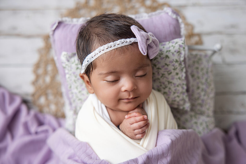Newborn baby peacefully sleeping in a lavender wrap during a professional newborn photography session at FrameIt Bay Area.