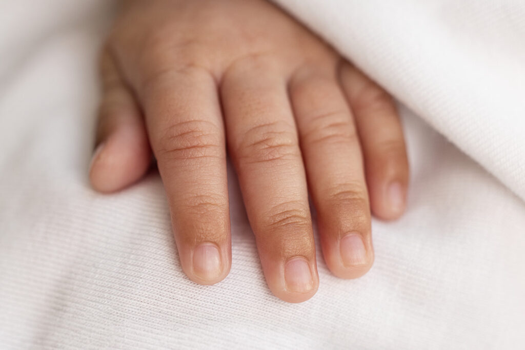 Close-up of a newborn baby’s tiny hand resting on a soft white blanket during a San Ramon newborn photography session.