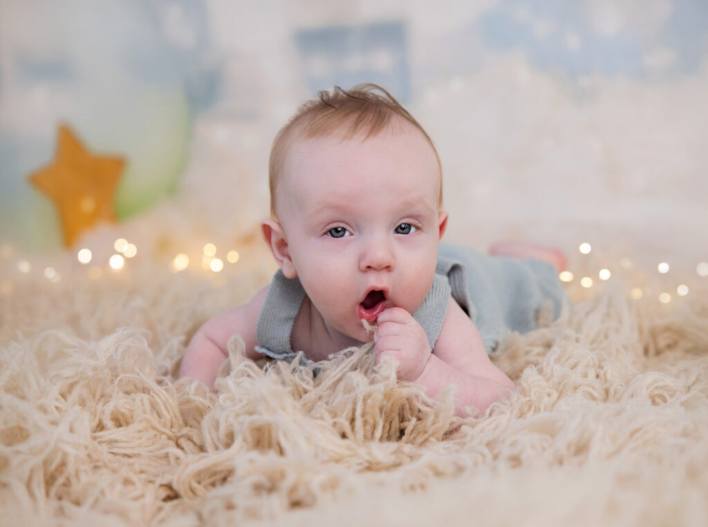 Six-month-old baby lying on a soft white blanket during a six-month baby photo session