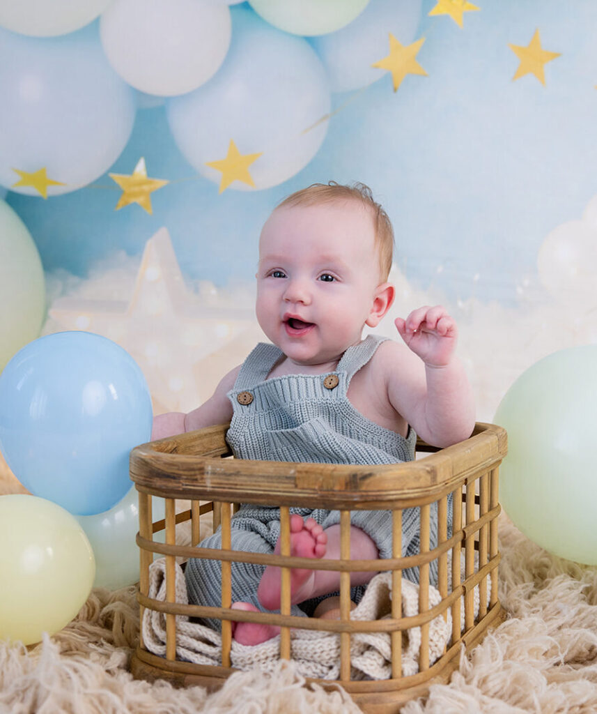 Six-month-old baby sitting among pastel balloons and gold stars during a six-month milestone session